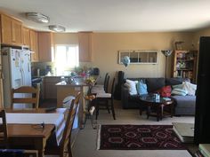 a living room filled with furniture next to a kitchen and dining room table in front of a refrigerator