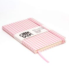 a pink and white checkered notebook on a white surface