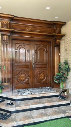 a large wooden door with two planters on the steps next to it in front of a brick wall