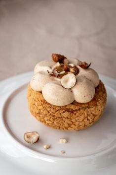 a white plate topped with a cupcake covered in icing and nuts on top of it