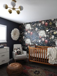 a baby's room with floral wallpaper and a crib in the corner