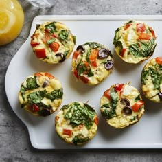 several small muffins with different toppings on a white platter next to an orange