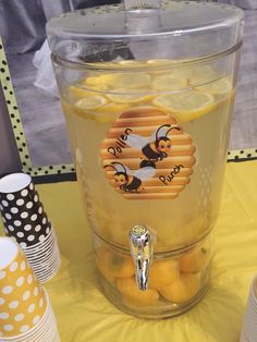 a jar filled with lemons sitting on top of a yellow tablecloth covered table