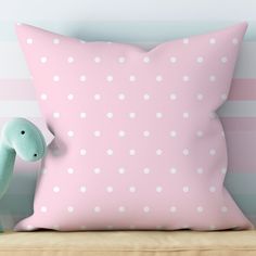 a pink pillow sitting on top of a wooden bench next to a green toy dinosaur