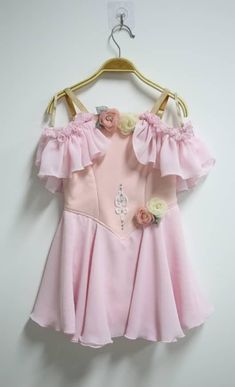 a pink dress hanging on a hanger with flowers in the front and bottom part of it