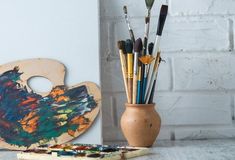 an easel with paint brushes in it next to a wooden duck