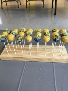 there are many yellow and blue cake pops on the stick in front of each other