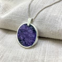 Charoite in a circular sterling silver pendant. This backless design allows both sides of the stone to be viewed. It won't matter which way the stone rests. This purchase comes with a 45cm sterling silver curb chain. Sterling Silver Necklace With Large Circular Pendant, Sterling Silver Circular Necklace With Large Pendant, Sterling Silver Circle Necklace With Large Pendant, Purple Sterling Silver Necklace With Polished Finish, Sterling Silver Jewelry With Large Stone, Silver Circle Gemstone Jewelry, Spiritual Sterling Silver Necklace With Round Stone, Sterling Silver Necklace With Large Oval Stone, Oval Sterling Silver Necklace With Large Stone