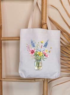 a white tote bag with flowers in a mason jar on the front and bottom