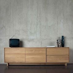 a television sitting on top of a wooden cabinet next to a vase and other items