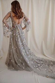 a woman in a dress with stars on it is looking back at the camera while standing against a white backdrop