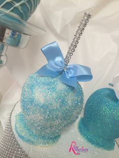 there is a blue and white cake with a bow on it's top, next to some other items