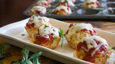 small appetizers with meat and cheese are on a white plate next to a muffin tin