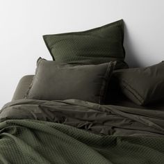 a bed with green sheets and pillows on it