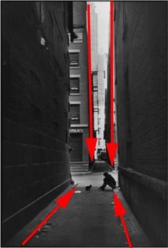 an alley way with red arrows going up and down the wall, leading to a person kneeling on the ground