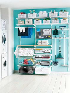 an organized laundry room with blue walls and white shelves