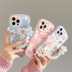 three phone cases with flowers on them are being held up by two woman's hands