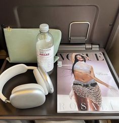 a magazine, headphones and purse on an airplane seat with the cover pulled down