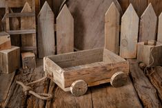 an old wooden box with wheels and rope on a table next to other wood blocks