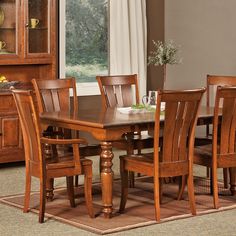 a dining room table and chairs with a rug on the floor in front of it