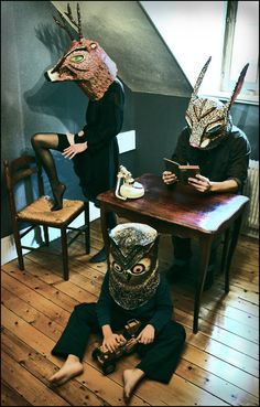 two people wearing masks sitting at a table with an open book in front of them