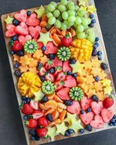 a wooden cutting board topped with cut up fruits and veggies on top of it