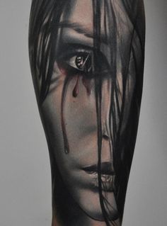 a woman's arm with a black and grey tattoo on it, featuring an evil face