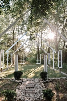 the sun shines through the trees in front of an open air pavilion with stone walkway