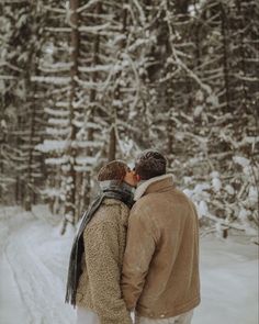 two people standing in the snow kissing each other