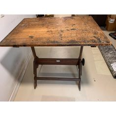 an old wooden table sitting on top of a hard wood floor next to a wall