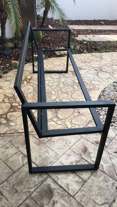 three black metal tables sitting on top of a stone floor next to a palm tree