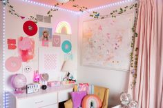 a bedroom decorated in pink and white with lots of decorations on the wall, including lights