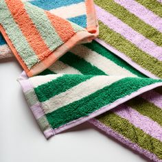 three towels folded on top of each other in different colors and patterns, one is orange, the other green