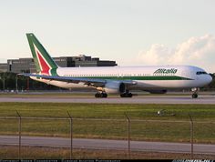 an air plane is on the runway in front of a large building and grassy area