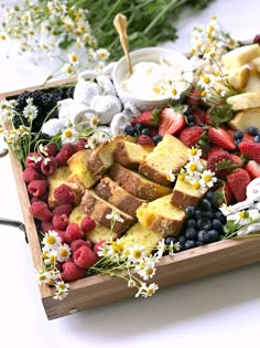 a wooden tray filled with different types of fruit and cake on top of a table