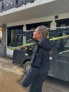 a woman holding skis in front of a hotel