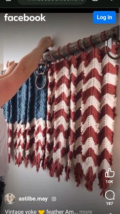 someone is holding up an american flag curtain to hang it on the wall in front of them