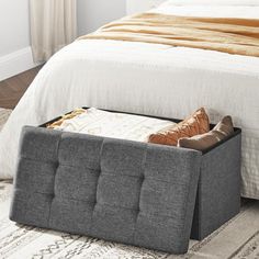 a bed sitting next to a white rug and a gray storage box on the floor