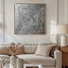 a living room filled with furniture and a large metal wall art hanging on the wall