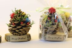 three small pine cones wrapped in plastic and decorated with christmas decorations are sitting on top of each other