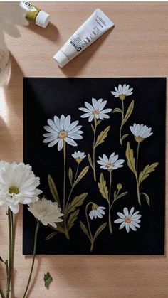 some white flowers are sitting on a table next to paintbrushes and water bottles