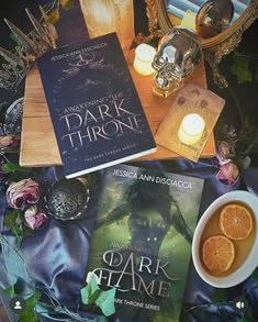 some books are laying on a table next to a cup of tea and an orange slice