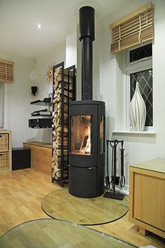 a wood burning stove sitting inside of a living room next to a firewood rack