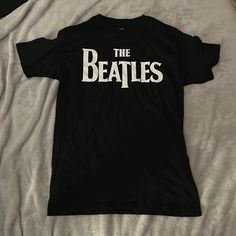 the beatles t - shirt laying on top of a bed