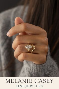 a woman's hand wearing a gold ring with a pear shaped diamond