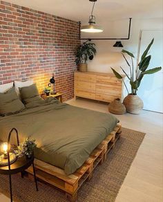 a bedroom with brick wall and green bedding in front of a large wooden table