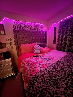 a pink and black bedroom with lights on the headboard, leopard print bedspread