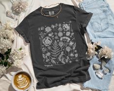 ✨ Flaunt your unique style with our aesthetic tees! This Instagram-worthy design is printed with eco-friendly inks on the bestselling 100% cotton Comfort Colors t-shirt. Step up your selfie game with this roomy top that feels like a well-worn favorite the moment you put it on. ✨ SIZING * Please refer to the size chart in the listing photos for exact measurements. * Better yet, simply lay out your favorite t-shirt and measure it, comparing it to our size chart. * This is a relaxed fit unisex size Botanical Screen Print Crew Neck T-shirt, Botanical Style Relaxed Fit Graphic Print Shirt, Botanical Relaxed Fit Graphic Shirt, Botanical Graphic Print Relaxed Fit Shirt, Relaxed Fit Botanical Graphic Print Shirt, Black Botanical Graphic Print Tops, Black Botanical Tops With Graphic Print, Botanical Graphic Print Cotton Shirt, Botanical Crew Neck Top With Graphic Print