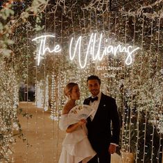 a bride and groom standing in front of a neon sign that says the williamss