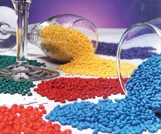 colorful beads and wine glasses sitting on a table next to each other with one glass in the middle